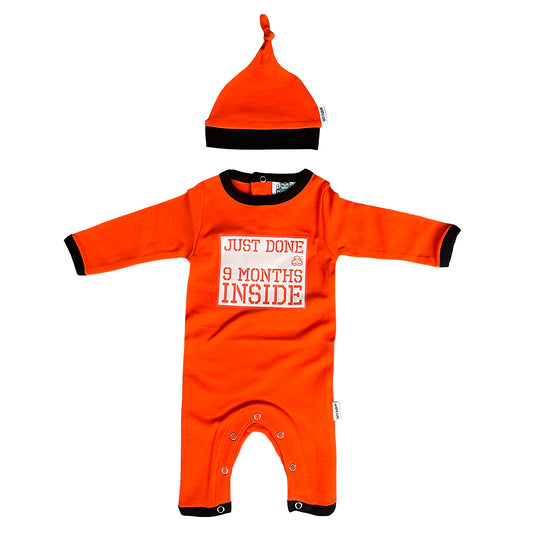 An orange prison baby grow and hat outfit with the text 'Just done 9 months inside' printed on the grow, and a black and orange hat with a knot on top.