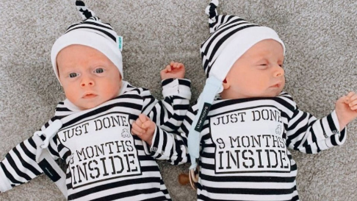 Twins wearing Just Done 9 Months Inside baby grows and matching stripy Lazy Baby hats