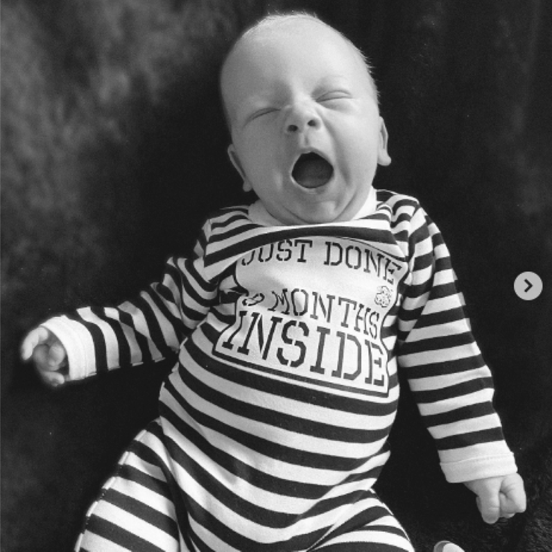 Yawning baby wearing Just Done 9 Months Inside baby grow