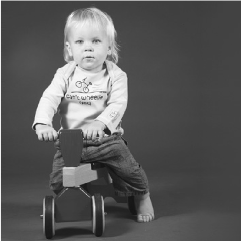 Baby riding trike wearing Can't Wheelie Yet top