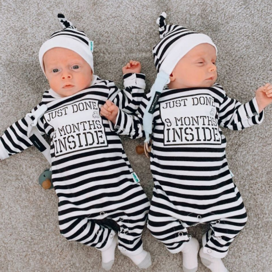 Twins wearing Lazy Baby stripy black and white hats with matching Just Done 9 Months Inside baby grows